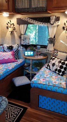 the inside of a camper with two beds and a table in front of it