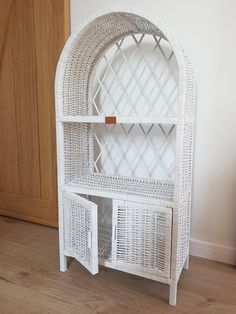 a white wicker book shelf with two baskets on the top and one drawer open