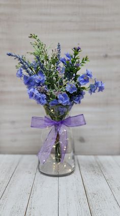 blue flowers in a clear vase with purple ribbon