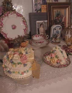 a table topped with plates and cakes covered in frosting next to pictures on the wall