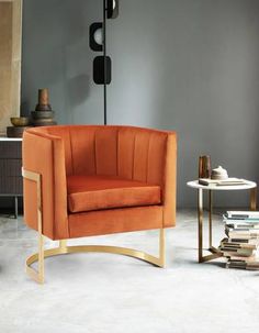 an orange chair sitting in a living room next to a table with books on it