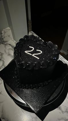 a black heart shaped cake sitting on top of a table