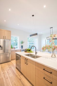 a kitchen with an island and stainless steel appliances in the center, surrounded by wood flooring