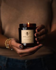 a woman holding a candle in her hands with a bee on the front and side