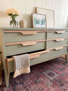 a green dresser with two drawers and a pink rug