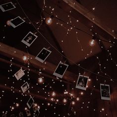 several polaroid frames are hung on a string with fairy lights strung from the ceiling