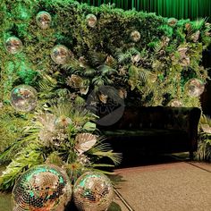 disco balls and plants in front of a green curtain