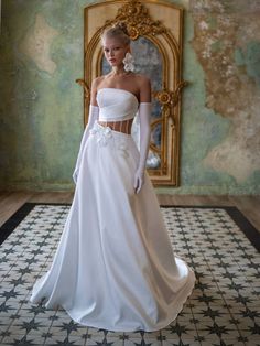 a woman in a white dress standing on a tiled floor