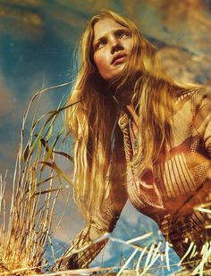 a woman with long hair is kneeling in the grass