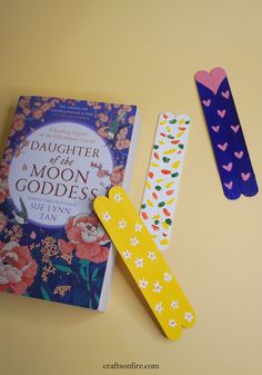 two bookmarks made out of paper next to a children's book and ruler