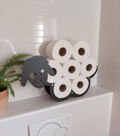 several rolls of toilet paper sitting on top of a shelf next to a potted plant