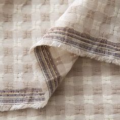 a close up view of a white and beige fabric with small squares on the edges