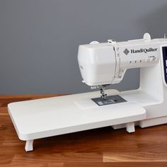 a white sewing machine sitting on top of a wooden table