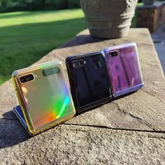 three different colored cases sitting on top of a rock