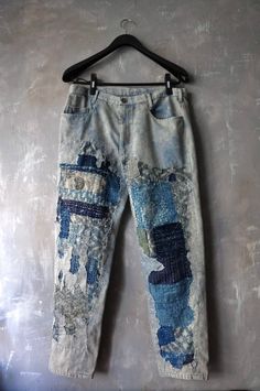 an old pair of jeans is hanging on a hanger with some paint splatters all over it