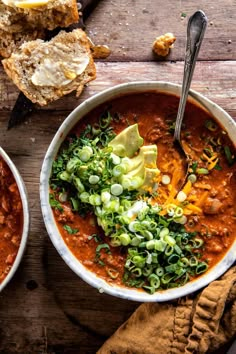 two bowls of chili with bread on the side