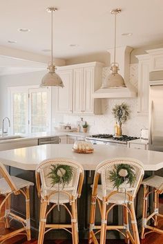 an island in the middle of a kitchen with four stools and two lights above it