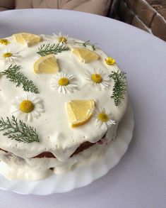 a cake decorated with lemons and daisies on a plate