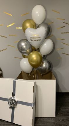 a gift box with balloons and a bunch of silver and gold foiled balloons in it