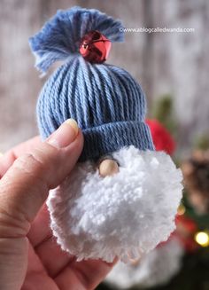 a hand holding a small white and blue knitted ornament