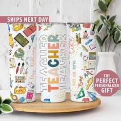 three personalized tumbles with the words happy teacher on them, sitting next to a potted plant