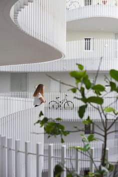 there is a woman that is walking down the stairs in front of a building with white balconies