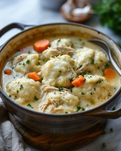 a pot filled with dumplings and carrots on top of a table