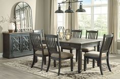 a dining room table and chairs in front of a window with an area rug on the floor