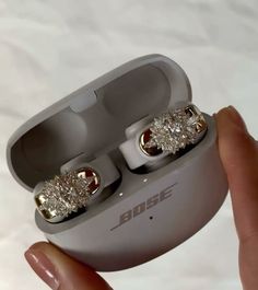 a person is holding an earphone with two diamonds in it's case on a white surface