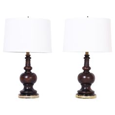 two wooden table lamps with white shades on each lamp and one is turned off to the side