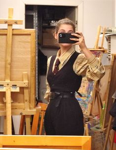 a woman taking a selfie in front of an easel