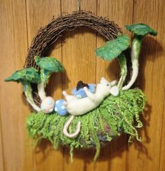 a close up of a wreath on a wall with animals in the grass and leaves