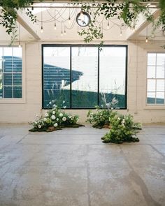 flowers and greenery are arranged on the floor in an empty room with large windows