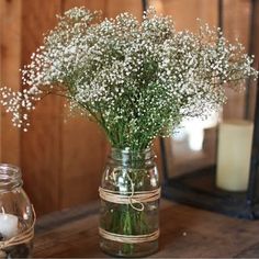 a mason jar filled with baby's breath sitting on top of a wooden table