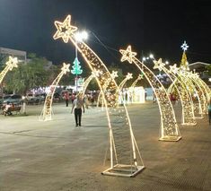 lighted archways in the middle of a street at night with people walking around them