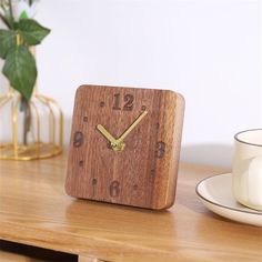 a wooden clock sitting on top of a table next to a cup and saucer