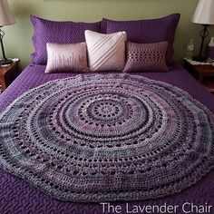 a bed with purple bedspread and two lamps