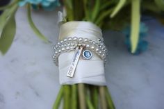 a boutonniere with pearls and a name tag on it sitting next to some flowers