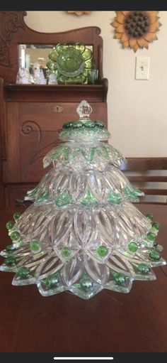 a glass christmas tree sitting on top of a wooden table