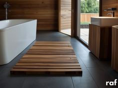 a bath tub sitting next to a white sink in a room with wooden floors and walls