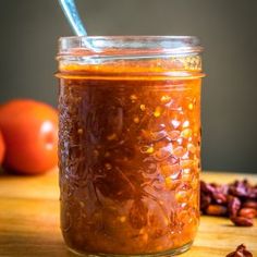 a glass jar filled with food sitting on top of a wooden table next to tomatoes