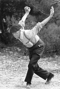 a man is doing a handstand in the middle of a dirt area with trees in the background