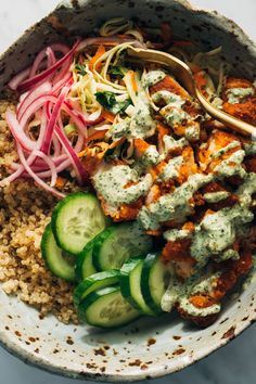 a bowl filled with rice, cucumbers and sauce