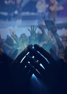 hands reaching up in front of a crowd at a concert