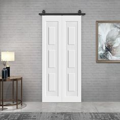 an empty room with a white door and grey brick wall, side table and lamp