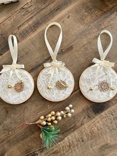 three white doily ornaments with bows on top of a wooden table next to pine cones