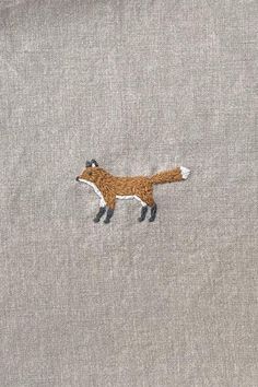 an embroidered fox is on the back of a gray shirt