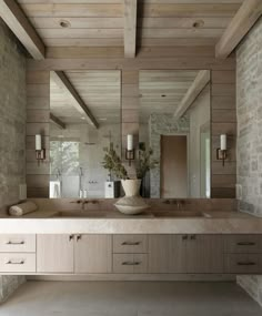 a bathroom with two sinks and mirrors in it's center wall, surrounded by stone walls