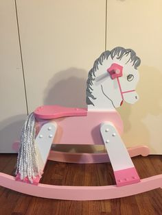 a pink and white rocking horse sitting on top of a wooden floor