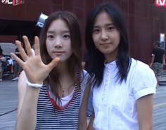 two young women standing next to each other with their hands up in front of them